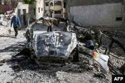 Seorang pria Palestina berjalan melewati kendaraan yang hancur di Jenin setelah serangan pasukan Israel di kota Tepi Barat yang diduduki pada 23 Mei 2024.