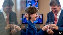 Sen. Susan Collins, R-Maine, left, and Sen. Joe Manchin, D-W.Va., right, clink glasses in a toast to each other after the Senate reached an agreement to advance a bill ending US government shutdown. (AP Photo/Andrew Harnik)