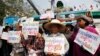 Farmers hold signs in front of a combine harvester during a rally demanding the Yingluck administration resolve delays in payment from the rice pledging scheme outside the Commerce Ministry in Nonthaburi province, on the outskirts of Bangkok, Feb. 6, 2014