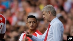 Manajer Arsenal, Arsene Wenger (kanan), memberi instruksi pada Alexis Sanchez dalam sebuah pertandingan melawan Benfica di London.