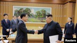 Pemimpin Korea Utara Kim Jong Un berjabat tangan dengan Chung Eui-yong yang memimpin delegasi Korea Selatan, dalam foto yang dirilis kantor berita pemerintah Korea Utara (KCNA), 6 Maret 2018.