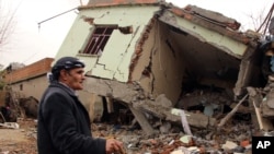 Seorang warga berjalan di rumah yang hancur di kota Silopi, Turki, yang penduduknya sebagian besar Kurdi, 19 Januari 2016.