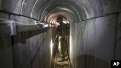 FILE - In this July 25, 2014, photo, an Israeli army officer gives journalists a tour of a tunnel allegedly used by Palestinian militants for cross-border attacks, at the Israel-Gaza Border.