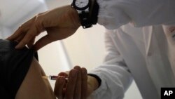 FILE - Doctor Roberto Ieraci vaccinates a woman in Rome as Italy battles one of its worst epidemics of measles in recent years, Feb. 23, 2018. 