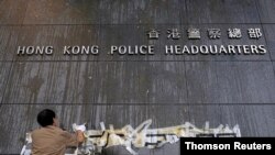 Staff try to clean off marks from thrown eggs and anti-extradition graffiti on the walls of the Hong Kong Police headquarters in Hong Kong, June 22, 2019.
