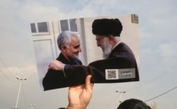 A man holds a picture of Iran's supreme leader Ali Khamenei with Iranian Revolutionary Guards top commander Qasem Soleimani (L) during a demonstration in Tehran, Jan. 3, 2020 against the killing of the top commander in a US strike in Baghdad.