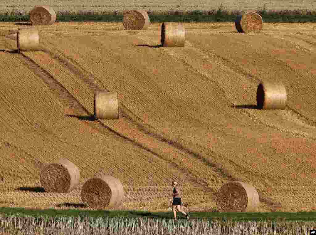 A woman runs by rolls of straw on a field in Frankfurt, Germany.