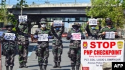 Police personnel hold up placards reminding people to stay at home amid concerns of the spread of the COVID-19 coronavirus in Manila on March 31, 2020. - The main Philippine island of Luzon, home to 55 million people which includes the capital…