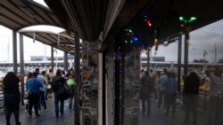 FILE - People queue to cross into the United States at the San Ysidro crossing port on the Mexican side of the U.S.-Mexico border in Tijuana, Baja Caifornia state, Aug. 20, 2021.