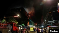 Sejumlah karyawan dievakuasi dan tamu hotel berdiri di sepanjang jalan dan menyaksikan kepulan asap dari gedung Resorts World di Pasay City, Metro Manila, Filipina 2 Juni 2017.