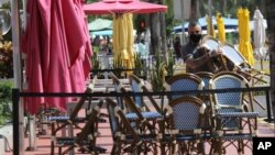 An employee at the Clevelander bar and restaurant on Ocean Drive stacks chairs, July 13, 2020, in Miami Beach, Fla. The business has shut down because of public health concerns caused by COVID-19 during the coronavirus pandemic.