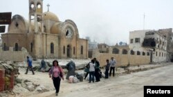Warga berjalan di defat gereja di wilayah Qusair yang hancur di Suriah, 8 Juni 2013 (Foto: dok). Kelompok oposisi utama Suriah menuduh pasukan pemerintah menempatkan senjata berat di Biara Cherubim, biara ortodoks bersejarah di utara Damaskus.