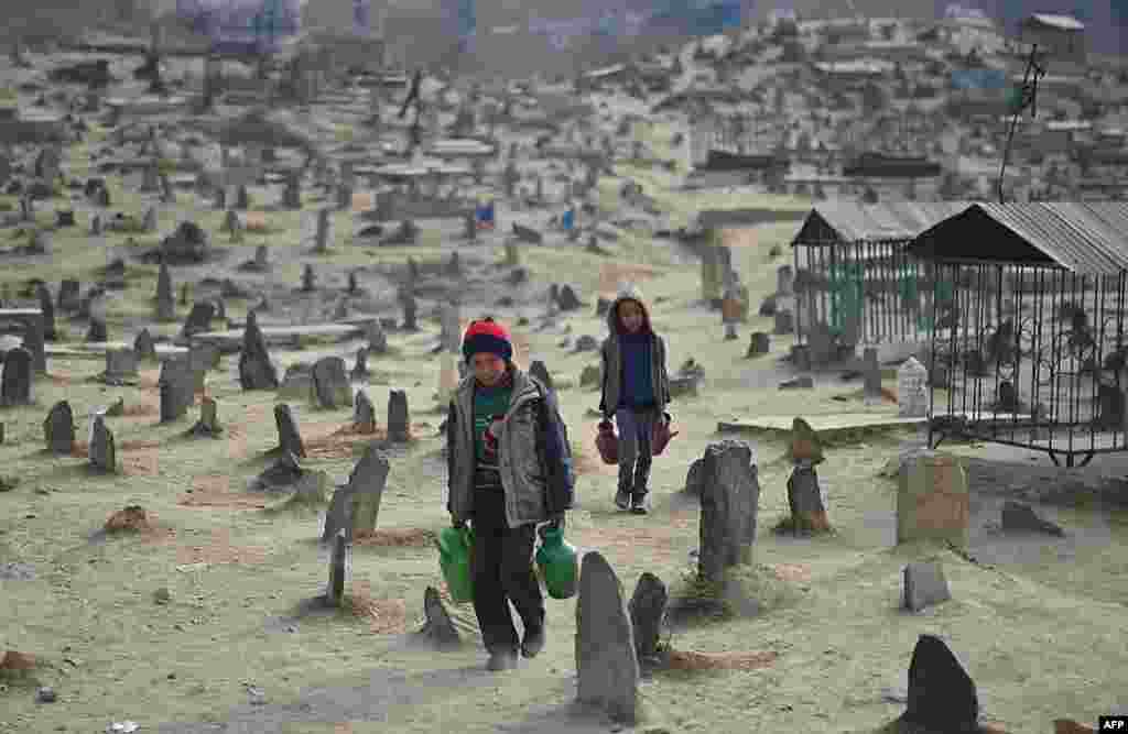 Anak-anak Afghanistan menawarkan air minum di tempat pemakaman umum Kart-e-Sakhi di Kabul.