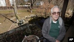 In this Friday, March 13, 2020 photo, Paul Buescher sits on his back porch, in Northfield Center Township, Ohio. Buescher is one of 32 members of a group in northeastern Ohio that shares a farm packed with enough canned and dehydrated food and water to last for years. (AP Photo)