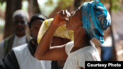 Woman drinking the first dose of the first oral vaccine against cholera in Africa during an epidemic, Guinea, Tougnifili/Mankountan, 2012. Photo by David Di Lorenzo/MSF. 
