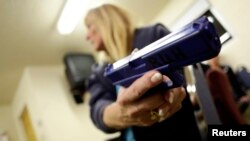 Une femme tient une arme de poing factice alors qu'elle assiste à un cours de formation sur la sécurité des armes à Phoenix, en Arizona, le 13 mars 2013.