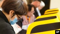 2020年3月3日超级星期二，一位戴口罩的选民在加利福尼亚州蒙特利公园市投票中心投票。