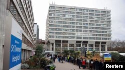 FILE - People queue outside a COVID-19 vaccination center at St Thomas's Hospital in London, Britain, Dec. 13, 2021.