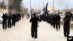 FILE - This undated file image posted on a militant website shows fighters from the al-Qaida linked Islamic State of Iraq and the Levant (ISIL) marching in Raqqa, Syria.