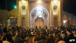 People gather outside the closed doors of the Fatima Masumeh shrine in Iran's holy city of Qom, March 16 2020. 