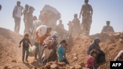 FILE - This handout picture taken on January 22, 2014 and released on August 29, 2014 by the (UNHCR) shows Syrian refugees who stream across the border into Jordan at a remote border point in the east. (AFP photo/UNHCR/Jared Kohler)