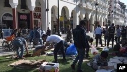 Migran membersihkan tempat penampungan sementara mereka di Aristotelous Square, Thessaloniki, Yunani utara, 8 Oktober 2018.