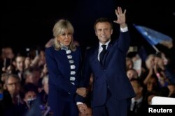 에마뉘엘 마크롱(오른쪽) 프랑스 대통령이 24일 대선 결선에서 승리, 재선을 확정한 직후 부인 브리지트 여사와 함께 파리 시내 에펠탑 앞에 모인 지지자들에게 인사하고 있다.
