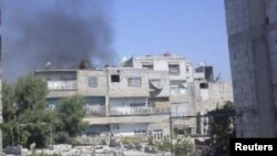 Asap tampak mengepul dari gedung di distrik Erbeen di pinggiran ibukota Damaskus, Suriah (foto: dok). 