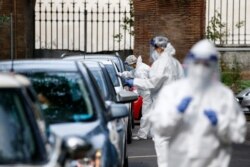 FILE - Medical staffers take swabs as they test for COVID-19 at a drive-through, in Rome, Oct. 13, 2020.