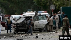 Afghan policemen investigate the site of a suicide attack in Kabul, June 6, 2014.