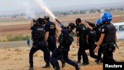 Turkish riot police fire tear gas to disperse pro-Kurdish protesters near the Turkish-Syrian border in the southeastern town of Suruc in Sanliurfa province, Sept. 29, 2014.