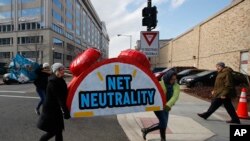 Protesters carry the top of an alarm clock display that reads "Net Neutrality" after a protest at the Federal Communications Commission in Washington, Dec. 14