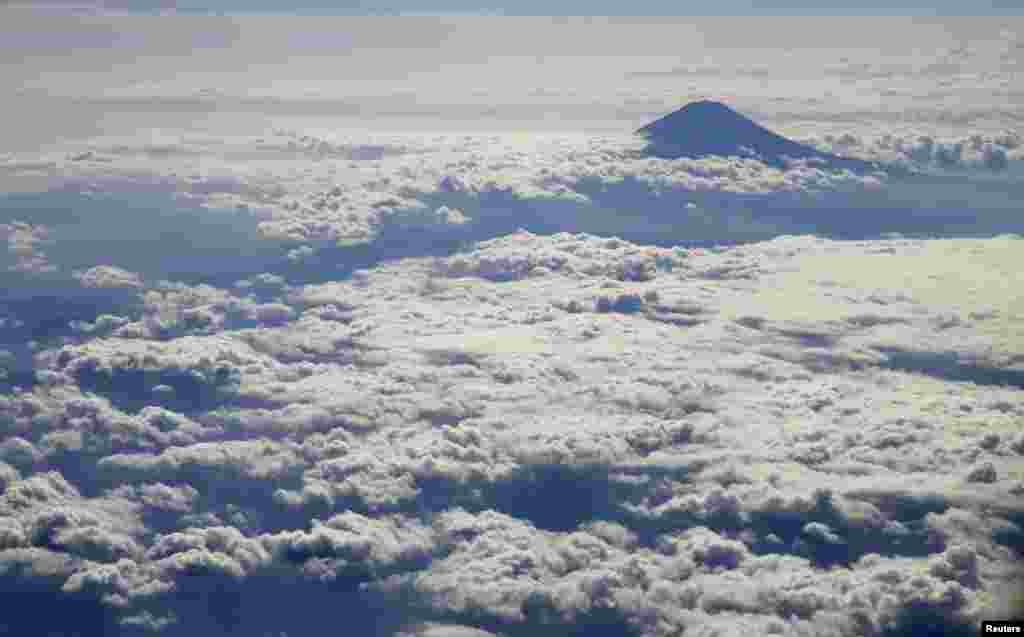 Japan&#39;s Mount Fuji, surrounded by clouds, is seen from an airplane