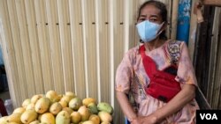 អ្នក​ស្រី​ បូ ផល្លី អង្គុយលក់​ស្វាយនៅ​មុខផ្ទះ​ក្នុង​បរិវេណ​វត្ត​ប្រយូរវង្ស​ នៅរាជធានីភ្នំពេញ កាលពី​ថ្ងៃអង្គារ​ ទី៣១ ខែមីនា ឆ្នាំ២០២០។ (ទុំ ម្លិះ/VOA)