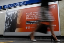 A woman walks past a sign with a message in Spanish: "Making sexual jokes about your female colleagues is also violence; together we can stop violence against women," inside a subway station in central Mexico City, March 5, 2020.