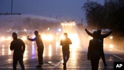 Nationalist youths gesture towards a police line blocking a road near the Peace Wall in West Belfast, Northern Ireland, April 8, 2021. 