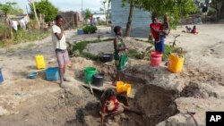 A woman fetches water from an unprotected source in Beira, Mozambique, Sunday, March, 31, 2019.