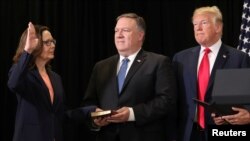 Gina Haspel diambil sumpahnya sebagai Direktur baru CIA, sementara Menteri Luar Negeri AS, Mike Pompeo memegang Kitab Suci dan Presiden Donald Trump menyaksikan upacara tersebut di markas Besar CIA di Langley, Virginia, 21Mei 2018.