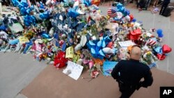 ប៉ូលិស​ម្នាក់​បាន​មក​ទីលាន​រំលឹក​វិញ្ញាណ​ក្ខន្ធ​បណ្តោះអាសន្ន​នៅ​ទីស្នាក់កណ្តាលរបស់​ប៉ូលិសនៅ​ទីក្រុង​​ Dallas កាលពីថ្ងៃទី ១១ កក្កដា​២០១៦។