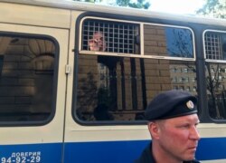 FILE - A police officer stands in front of a bus with reporters detained after a rally in Moscow, Russia, June 7, 2019.