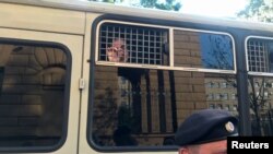 Arhiva - Policajac stoji ispred autobusa sa novinarima uhapšenim tokom mitinga u Moskvi, 7. jula 2019.