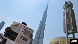 A man reads a copy of UAE-based The National newspaper near the Burj Khalifa in the gulf emirate of Dubai on August 14, 2020, as the publication's headline reflects the previous day's news about Israel. (Giuseppe CACACE / AFP)