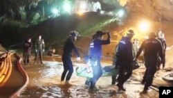 FILE - This undated from video released via the Thai NavySEAL Facebook Page on July 11, 2018, shows rescuers holding an evacuated boy inside the Tham Luang Nang Non cave in Mae Sai, Chiang Rai province, in northern Thailand.