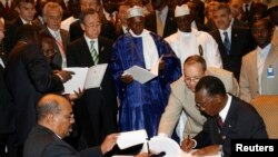 Le président soudanais Omar Hassan al-Bashir, à gauche en bas, et le président tchadien Idriss Deby, à droite, signent un accord de paix sous le regard du secrétaire général des Nations unies Ban Ki-moon (en haut) et du président sénégalais Abdoulaye Wade, centre, 13 mars 2008.