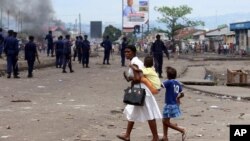 ARCHIVES - Une mère et ses enfants passent près de la police anti-émeute lors d'une manifestation à Kinshasa, en République démocratique du Congo, lundi 19 septembre 2016.