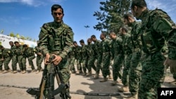Fighters of the U.S.-backed Kurdish-led Syrian Democratic Forces (SDF) dance as they celebrate near the Omar oil field in the eastern Syria, March 23, 2019, after announcing the total elimination of the Islamic State group's last bastion.