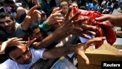 FILE - Syrian refugees and other migrants struggle to get dry food during aid distribution on the Greek island of Kos, Aug. 14, 2015. 