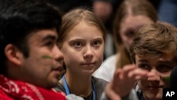 Aktivis perubahan iklim, Greta Thunberg (tengah), berbincang dengan sesama aktivis muda di konferensi iklim, COP25, di Madrid, 6 December 2019.