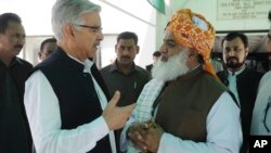 Pakistani Defense Minister Khawaja Muhammad Asif, left, confers with Jamat Ulema-e-Islam religious party leader Maulana Fazalur Rehman outside Parliament in Islamabad, April 10, 2015. Legislators decided not to join the Saudi-led coalition.