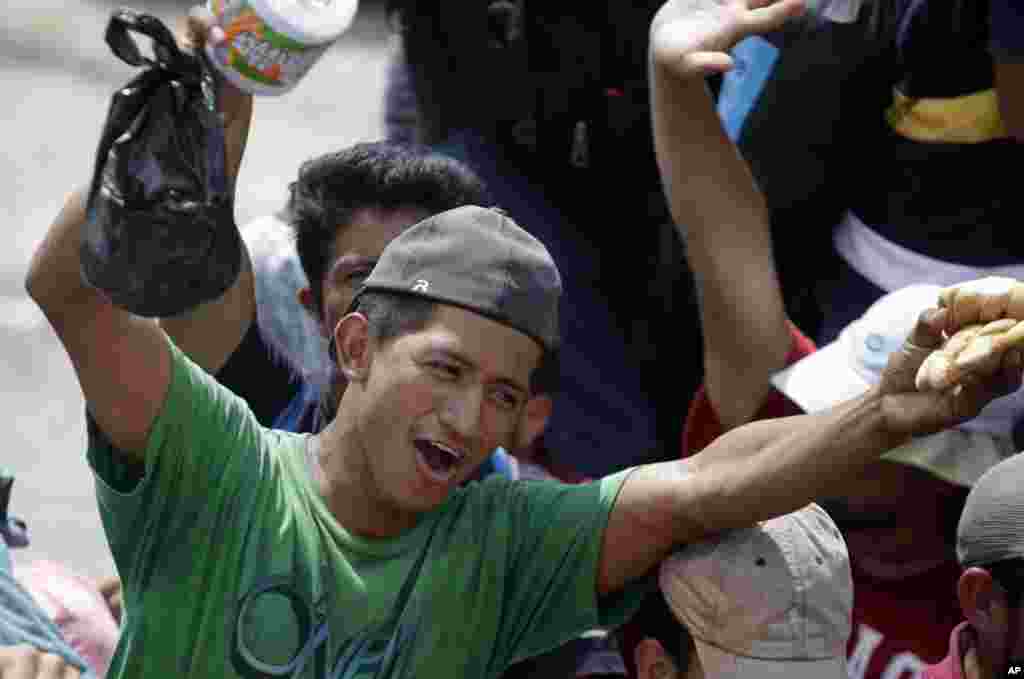 A Honduran migrant gets some food as a group of migrants traveling to the United States hitch a free ride in the back of a trailer truck flatbed to Teculutan, Guatemala, Oct. 17, 2018.